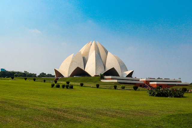 Lotus Temple seen from a distance with lush green grass in the foreground