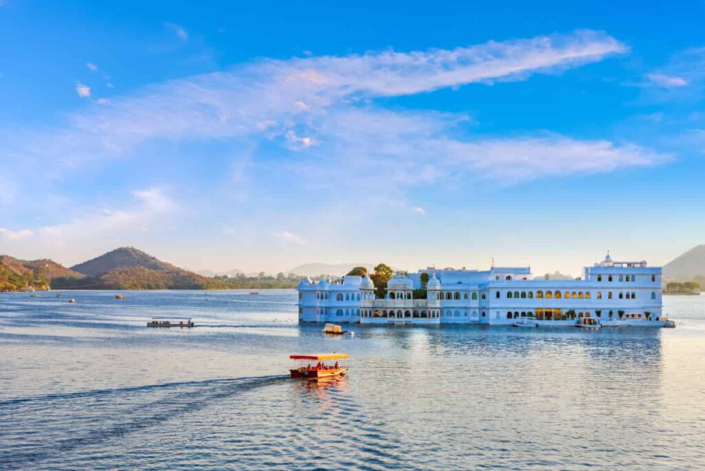 A serene view of Lake Pichola with crystal-clear blue water, showcasing the beauty of the lake and the surrounding landscape