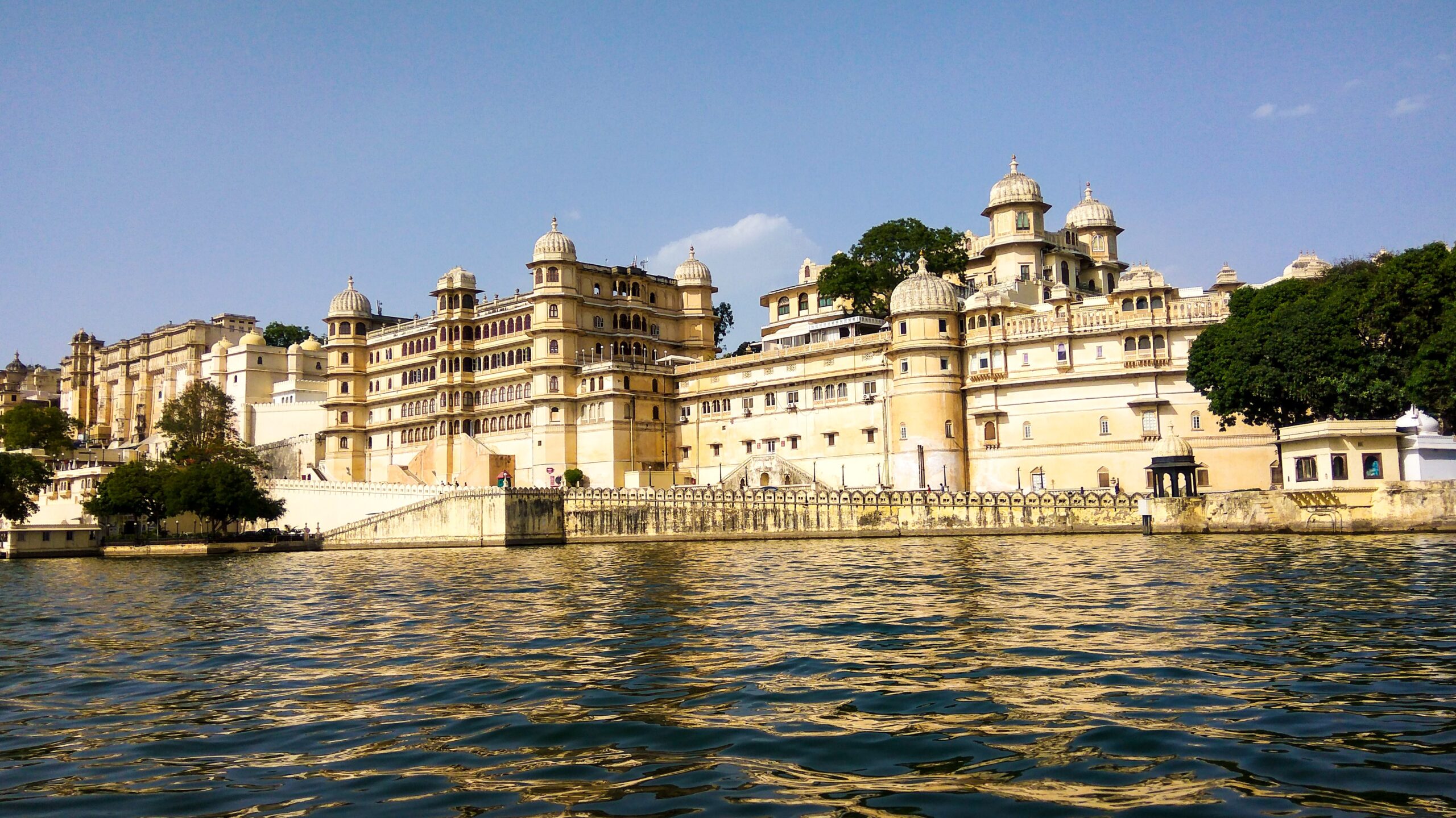 A scenic image of Udaipur's City Palace with a breathtaking view of the palace reflecting in the water, showcasing the architectural beauty against the tranquil backdrop