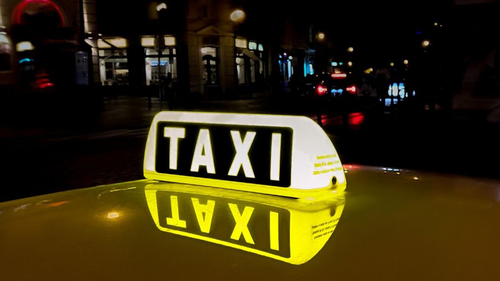 Illuminated Taxi Roof Sign shining brightly against the night sky, a beacon of convenience for travelers in the city