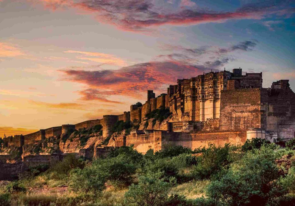 Aerial view of majestic Mehrangarh Fort with its towering walls against a cloudy sky, showcasing its architectural beauty.