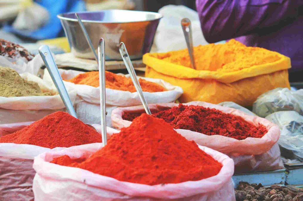 Assorted Indian spices including chili peppers, coriander seeds, turmeric, and more, showcasing vibrant colors and aromatic ingredients