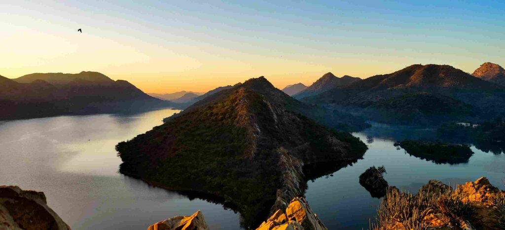 Panoramic view of Bahubali Hills, with water surrounding the hills and lush greenery covering the landscape. Image by Sumit Sharma, sourced from Unsplash