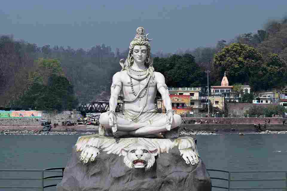 Lord Shiva meditating in a yogic posture on a lion's skin by the Ganges river, symbolizing strength and serenity. Image by Saurabh Kumar on Unsplash.