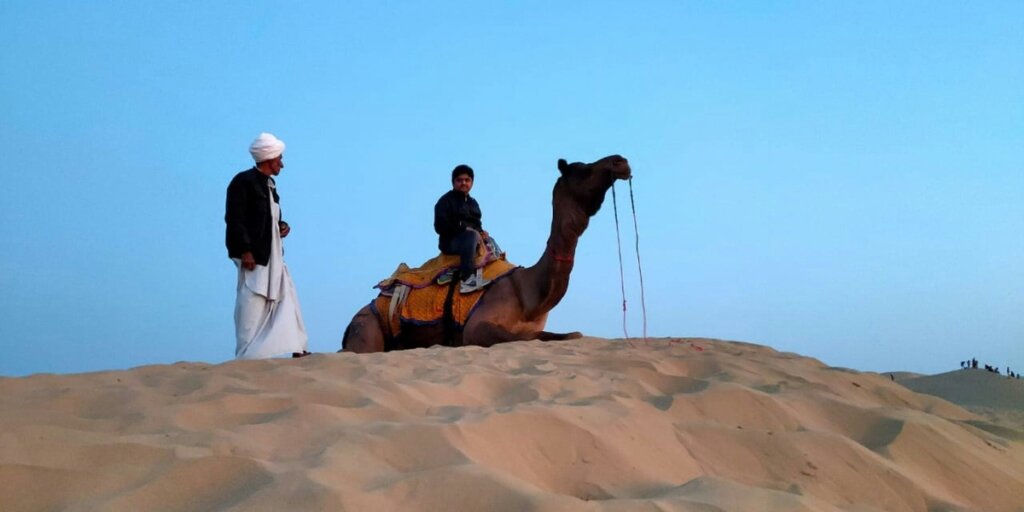 A child riding on a camel in the desert. Photo by Aayush Kaushik on Unsplash.