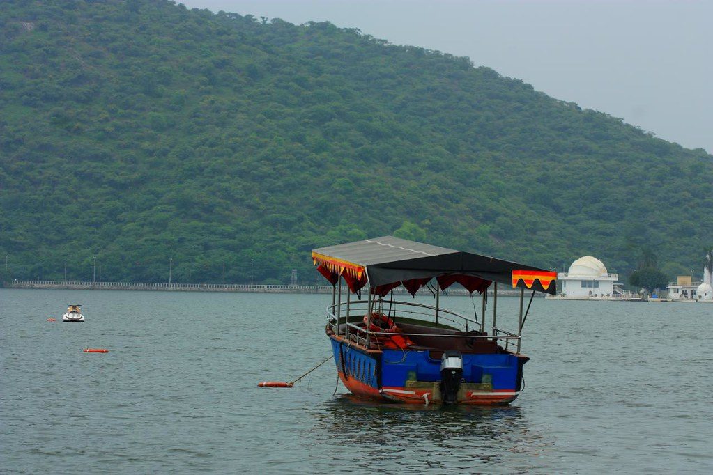 Boat ride on Fateh Sagar Lake, Udaipur, India. Serene waters surrounded by lush greenery and distant hills. Google Flickr.