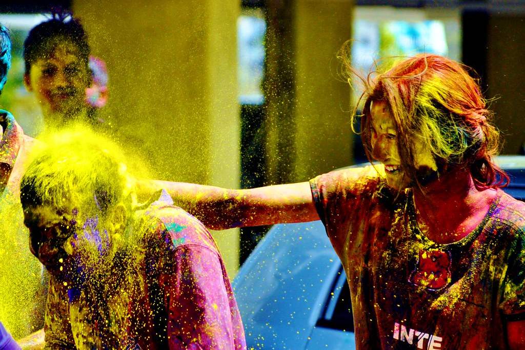 Holi celebration with people applying gulal (colored powder) on each other's heads - Image sourced from Flickr