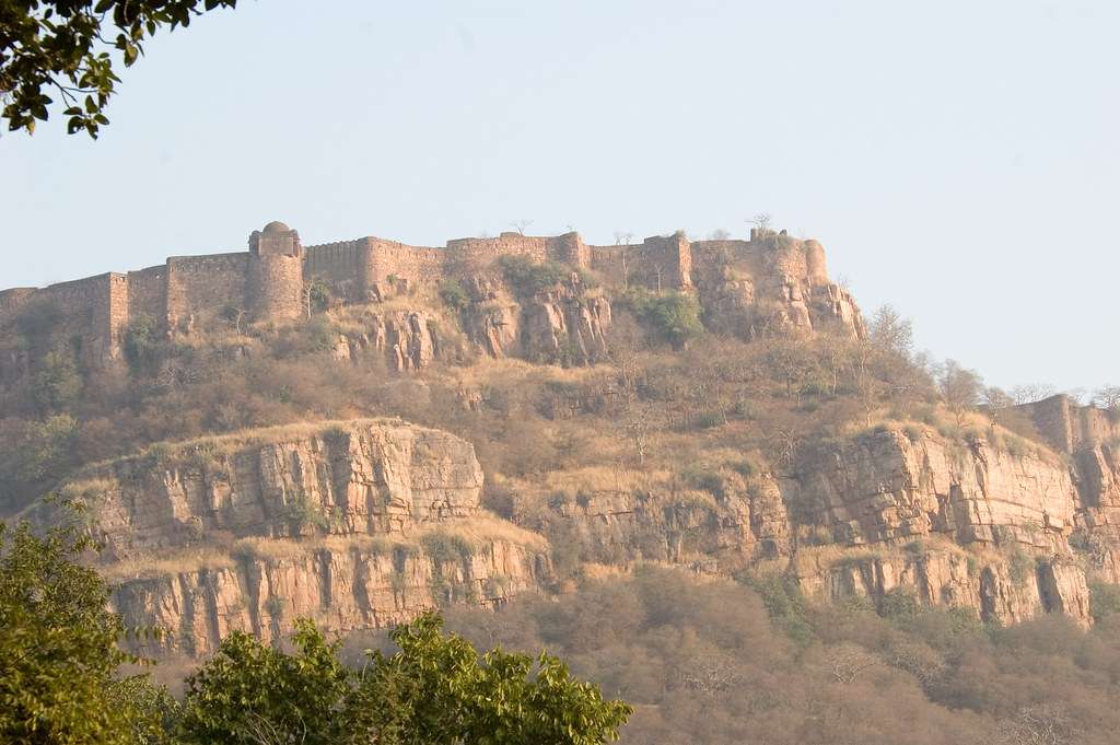 Exterior view of Ranthambore Fort, a historic hilltop fortress surrounded by lush greenery, taken from Flickr