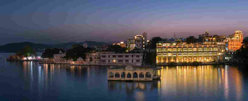 Lake Pichola, Udaipur image depicting a house on the water with city palace illuminated at night. Image by Siddhesh Mangela on Unsplash.