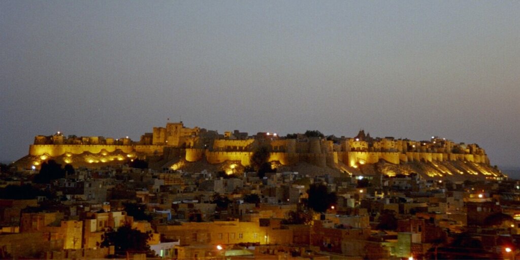  Illuminated Jaisalmer Fort glowing against the night sky, showcasing its majestic architecture and vibrant lighting, a symbol of Rajasthan's rich heritage and cultural splendor.