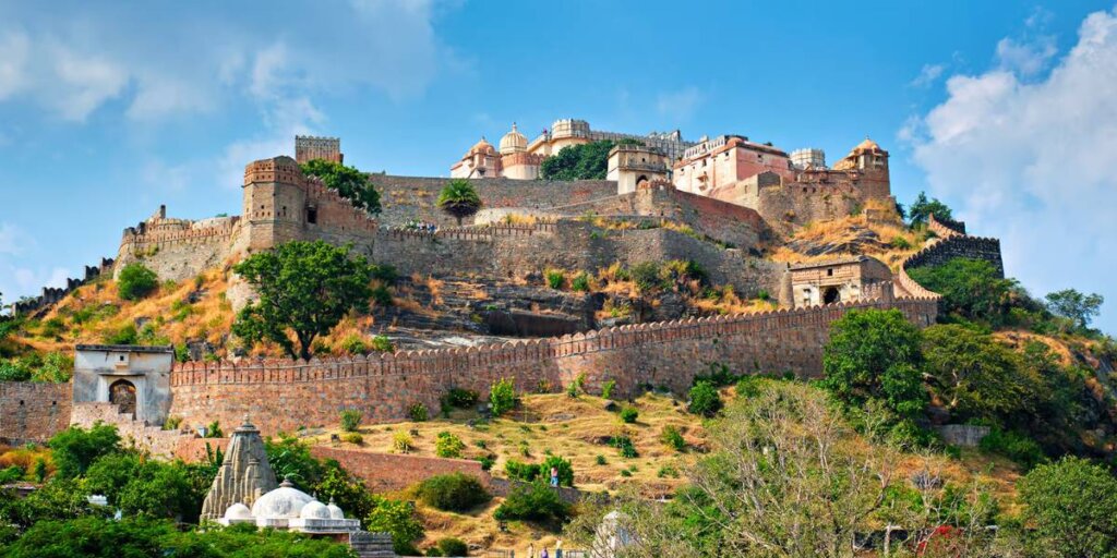 Aerial view of Kumbhalgarh Fort, surrounded by lush greenery and rugged terrain, showcasing its majestic architecture and historical significance.