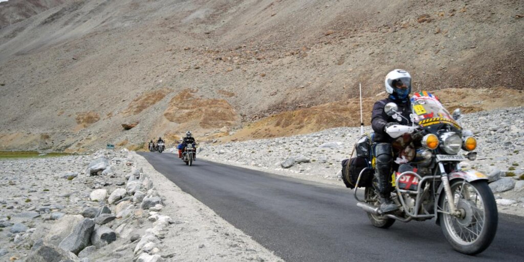 Pangong Lake road with people riding motorcycles, captured in a scenic image by Flickr.