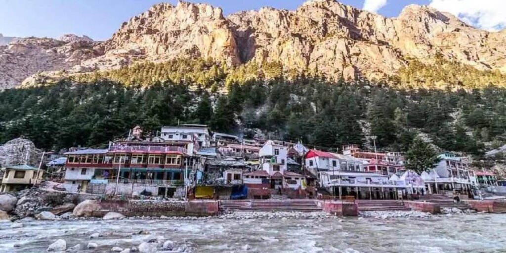 Aerial view of Gangotri, one of the Char Dham pilgrimage sites, showcasing the temple and houses nestled along the banks of the Ganges River in the Himalayas