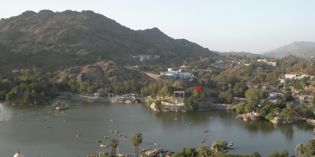 An aerial view of Nakki Lake in Mount Abu with the Bharat Mata statue situated at its edge, surrounded by lush greenery.