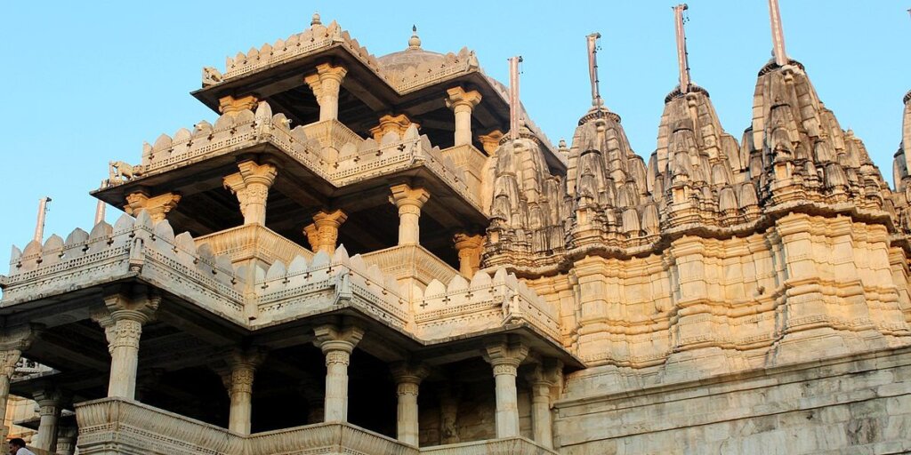 Image showcasing the Ranakpur Jain Temple in Pali, Rajasthan. The intricate marble architecture of the temple is visible against the backdrop of clear blue skies. Photo sourced from Wikimedia Commons.