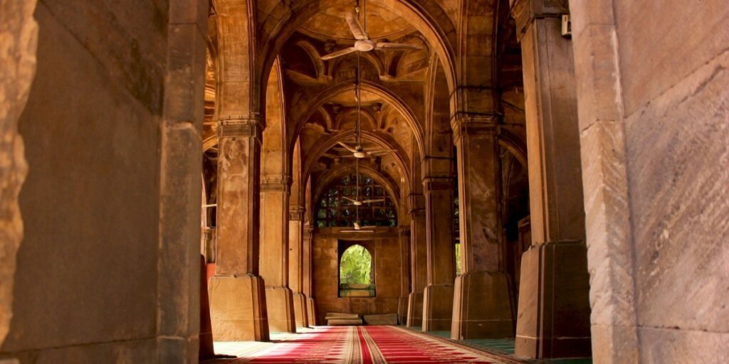 Exterior view of Sidi Saiyyed Mosque in Ahmedabad, featuring pillars and intricate carved stone lattice windows known as 'Jali'.