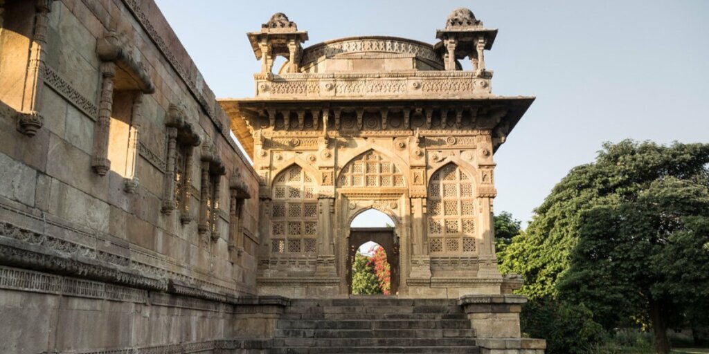 Image showing a palace in Vadodara, Gujarat. The palace has stone walls on the side and a large doorway in the front resembling a neck. Image by Rita Willaert.