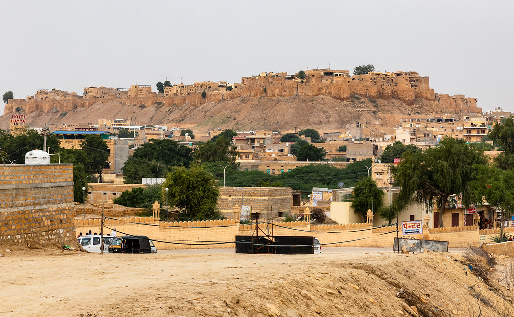 "View of Jaisalmer Fort from a distance, showcasing its impressive structure and golden limestone walls, photo by Ninara on Flickr."