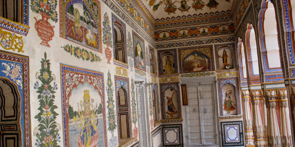 Photo of a haveli in Nawalgarh, Shekhawati, with ornate verandas and balconies adorned with intricate frescoes. In the foreground, there is a small, beautiful door, which adds to the traditional charm of the scene. Get this image: Flickr.