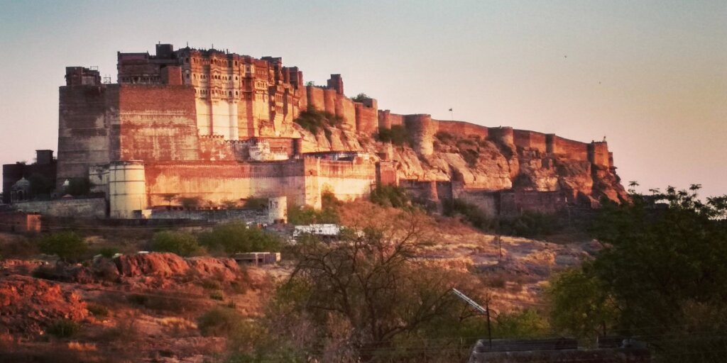 The imposing Mehrangarh Fort in Jodhpur, towering over the city with its massive walls and historic structures, under a clear blue sky.